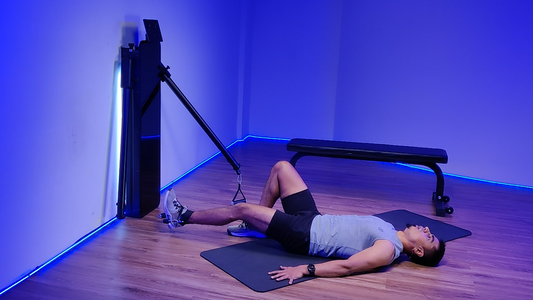 Man performing a lying down flexor pull exercise using a cable machine