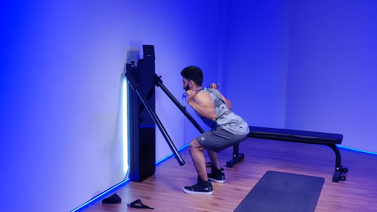 Man performing a back squat with a barbell in a gym setting.