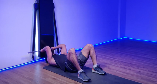 Man performing a Barbell Skull Crusher exercise, lying on a mat with a barbell overhead