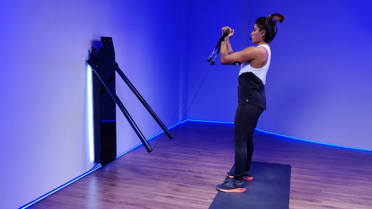 Woman using a Barn Doors machine for a workout, demonstrating bicep curls.