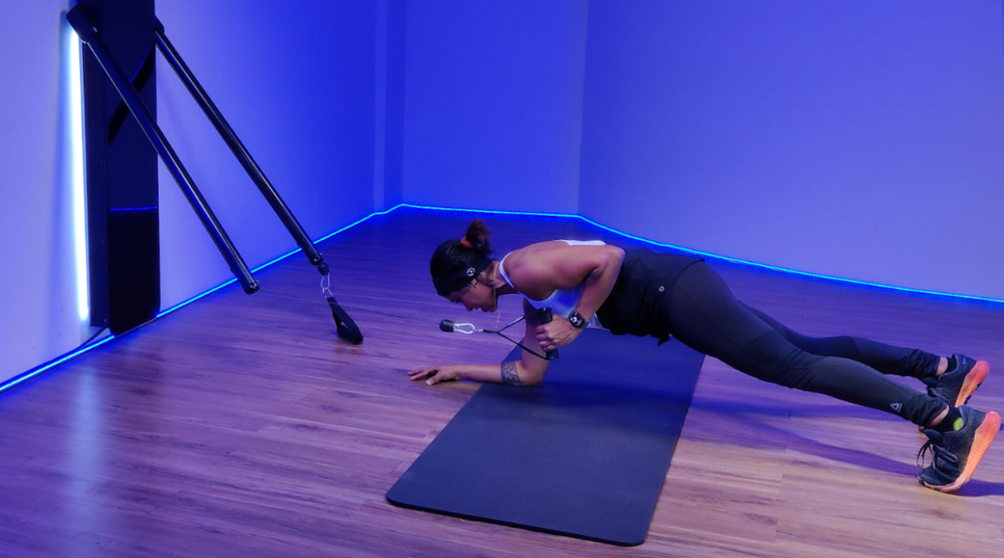 A woman performs a cable resisted plank hold, showcasing the proper technique and engaging core muscles.