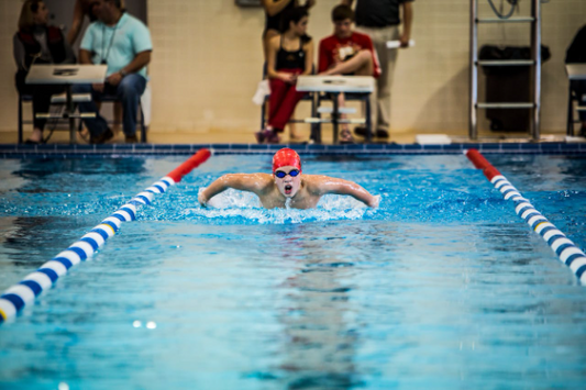 A swimmer demonstrating technique in a pool, exploring muscle development through swimming.