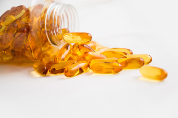 Fish oil capsules spread out from a bottle, showcasing skin benefits.