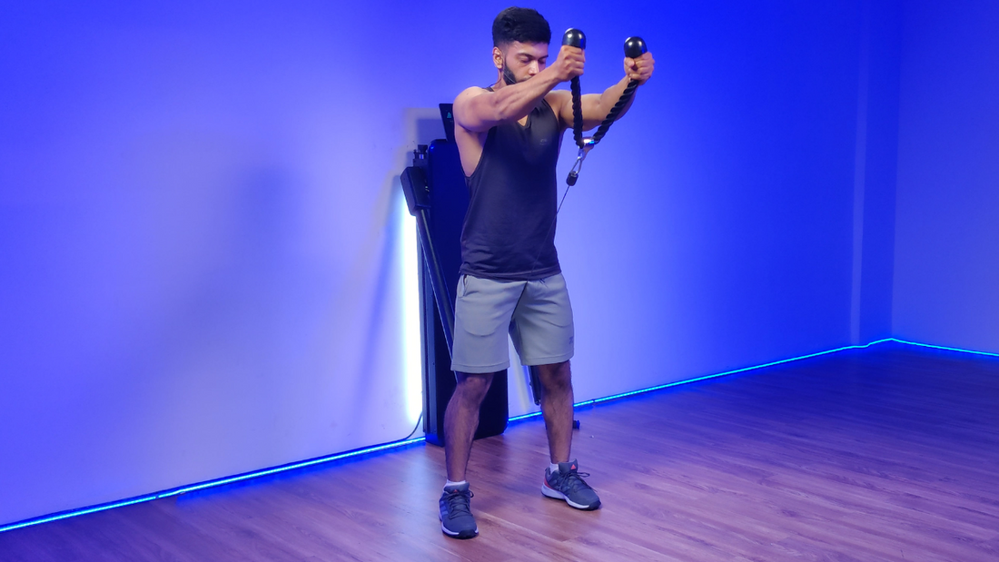 Man performing rope front raises exercise in a gym, targeting shoulder and chest muscles.