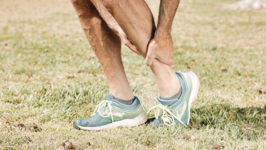 Person holding calf in pain, illustrating shin splints strength training.